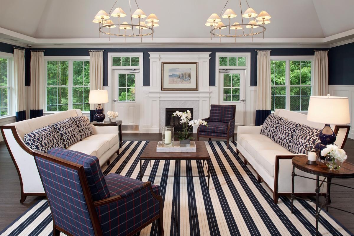 Clubhouse lounge with navy walls, twin chandeliers and fireplace