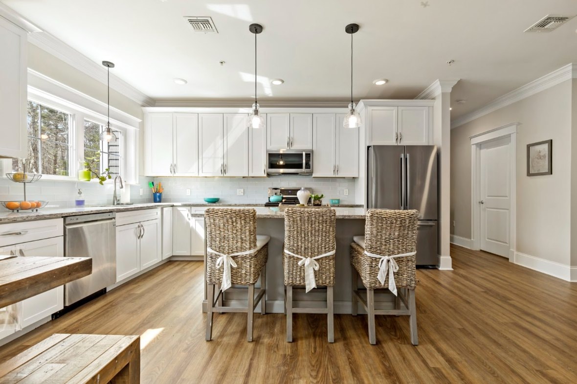 Single-level condo kitchen with white shaker cabinets, island seating, and hardwood floors